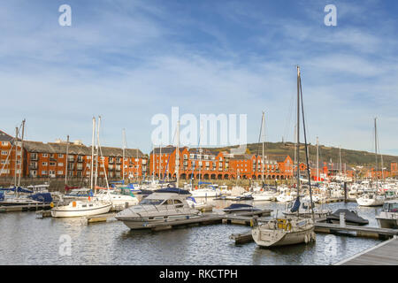 SWANSEA, WALES - Oktober 2018: Boote und Yachten in Swansea Marina mit Wohnblocks im Hintergrund. Stockfoto