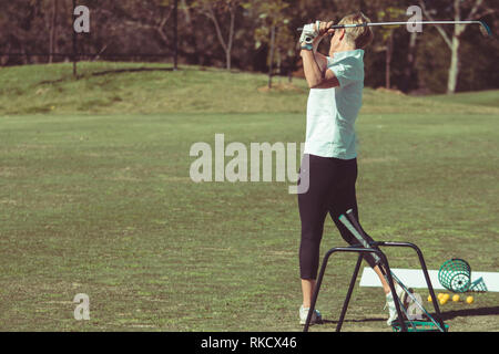 Frau Golf Spieler den Ball schlagen Stockfoto