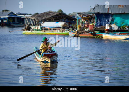 Tonlé Sap See, Kambodscha. 19. Dezember, 2018. Fischerin und ihre junge Tochter Zeile Vergangenheit schwimmende Häuser im Hintergrund. Foto: Bryan Watt Stockfoto