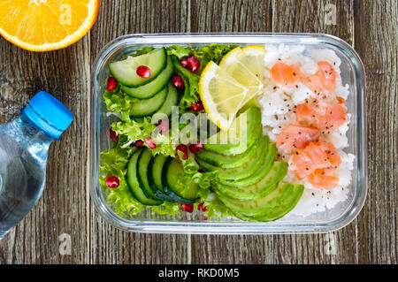 Mittagessen: Reis, Lachs, Salat mit Gurke, Avocado, grünen, Zitrone, Chia Samen und eine Flasche Wasser auf einem hölzernen Hintergrund. Fitness Nahrung. Das Konzept Stockfoto