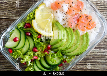Mittagessen: Reis, Lachs, Salat mit Gurke, Avocado, grünen, Zitrone, Chia Samen auf einer hölzernen Hintergrund. Fitness Nahrung. Das Konzept der gesunden Ernährung. Stockfoto