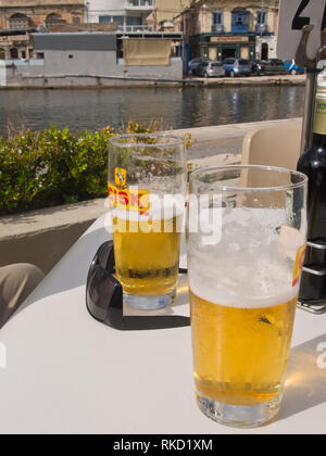 Halb voll - oder leere Gläser von cisk Bier auf einen freien Tisch in der Sonne, Urlaub auf Malta in der Nähe von Valetta Stockfoto