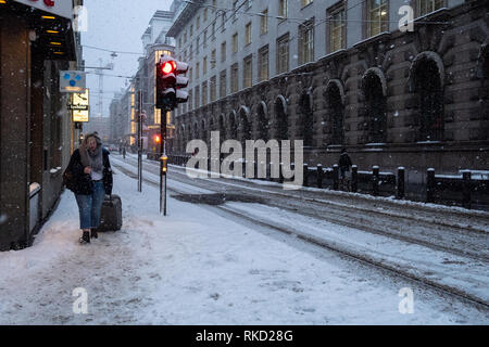 Frau mit Koffer, die durch die verschneiten Straßen in Oslo, Norwegen kämpft Stockfoto