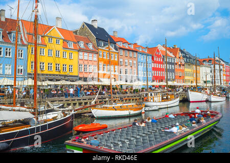 Tour segeln von Canal mit alten Segelboote im Hafen Nyhavn, Personen zu Fuß am sonnigen Ufer und Sitzen in Cafes und Restaurants, Kopenhagen, D Stockfoto