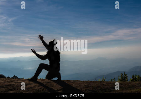 Die Silhouette eines Mannes, der über die Berge Landschaft beten Stockfoto