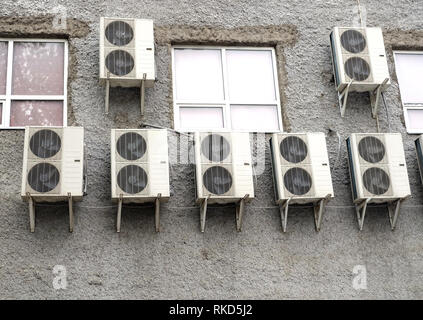 Viele industrielle Klimaanlage hängt sich auf grau, Rückwand der Gebäude mit geschlossenen Fenstern Vorderseite montiert Stockfoto