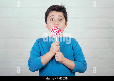 Überrascht Kind mit Lollipop auf Stein Hintergrund Stockfoto