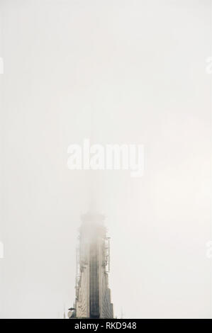 Eine Wolke und Nebel verdunkelte und verdeckte Spitze des ikonischen und symbolischen Empire State Building in New York City Manhattan. Stockfoto