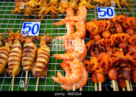 Eine Anordnung von spieß gegrillte Meeresfrüchte, bestehend aus Kalmare, Kraken, Tintenfische und geschälte Garnelen Thai Street Food Snacks und Vorspeisen in einen Fisch m Stockfoto