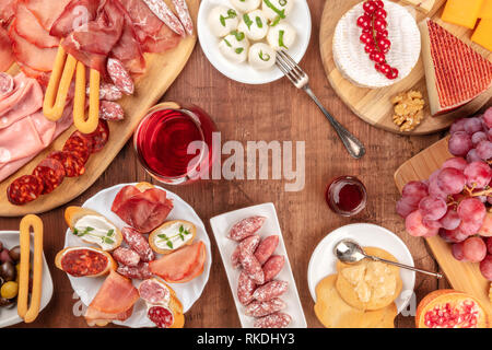 Charcuterie Verkostung. Ein Foto von vielen verschiedenen Wurst und Schinken, Aufschnitt und einer Käseplatte, geschossen von oben auf eine rustikale Hintergrund Stockfoto