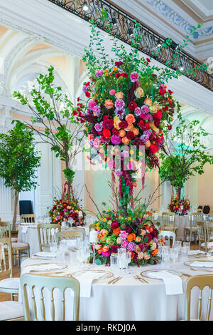 Hochzeit Tischdekoration. Schönen Blumenstrauß auf dem Tisch, neben Platten, kristall Gläser und Teller Stockfoto