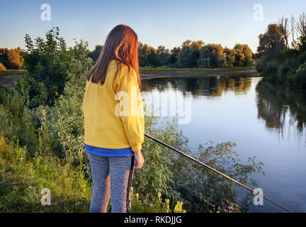 An den Ufern des Flusses am Abend das Mädchen Fisch mit Angel verfängt. Stockfoto