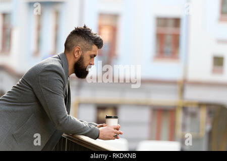 Stadt Lebensstil. Geschäftsmann gepflegt aussehen genießen Sie Kaffee Pause aus Business Center im städtischen Hintergrund. Entspannen und erholen Sie sich. Man bärtige hipster Kaffee trinken Pappbecher. Noch ein Schluck Kaffee. Stockfoto