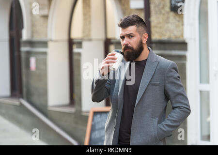 Kaffee trinken für Unterwegs. Geschäftsmann lumbersexual Erscheinungsbild genießen Sie Kaffee Pause aus Business Center. Entspannen und erholen Sie sich. Man bärtige hipster Pappbecher Kaffee trinken. Noch ein Schluck Kaffee. Stockfoto