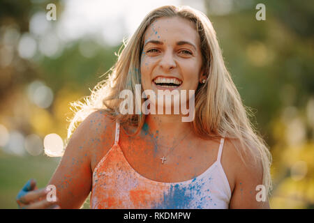 Lächelnde Frau mit Farben spritzte auf Ihren Körper spielen Holi. Glückliche Frau holi Spielen mit Puder Farben im Freien. Stockfoto