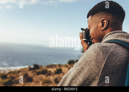 Afrikanischer Mann die Bilder von schönen Meereslandschaft mit seiner Digitalkamera. Mann schießen neue Inhalte für seine soziale Medien. Stockfoto