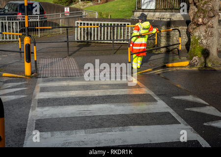 Lollipop, weibliche Verkehrsaufseherin, die an einem Fußgängerübergang wartet, um Schülern beim Überqueren der Straße in New Road, Killarney, County Kerry, Irland zu helfen Stockfoto