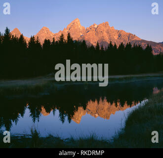 USA, Wyoming, Grand Teton National Park, Sonnenaufgang auf dem Gipfel der Teton Range, die in eine ruhige Seite Kanal des Snake River reflektieren. Stockfoto