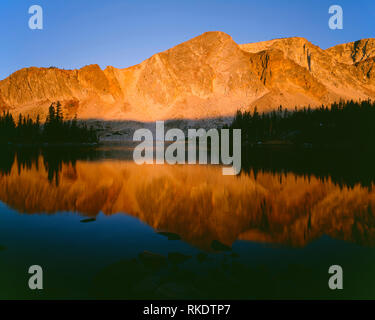 USA, Wyoming, Medizin Bug Routt National Forest, Sonnenaufgang auf Medizin Bug Peak spiegelt sich in ruhigem Wasser der See Marie in den Snowy Range. Stockfoto