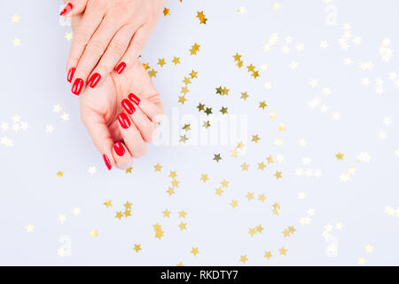 Frau mit roten Maniküre auf blauem Hintergrund mit Streuseln. Urlaub, Party und Feier Konzept. Horizontale Stockfoto