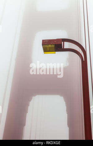 Das Licht post am Golden Gate Bridge, mit der Bridge Tower Eintauchen in den Nebel im Hintergrund, San Francisco, Kalifornien, USA Stockfoto