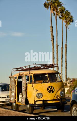 Classic 1960s gelb Volkswagon VW minibus Wohnmobil bei Sonnenuntergang Klippen bei Sonnenuntergang geparkt, Türen öffnen mit Palmen, San Diego, USA Stockfoto