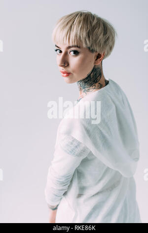Attraktive blonde Frau mit Tattoo am Hals stehen isoliert auf Grau Stockfoto