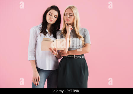 Studio konzentrierter Mädchen lesen Buch isoliert auf Rosa Stockfoto