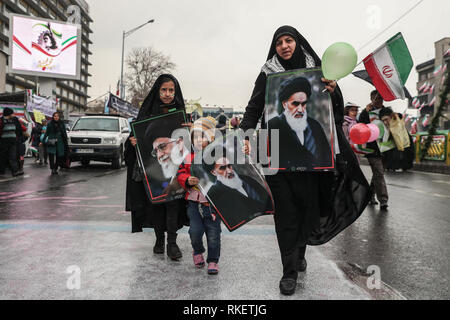 Teheran, Iran. 11 Feb, 2019. Eine Frau und ihre Kinder halten Bilder von Ayatollah Khomeini, ehemaliger Oberster Führer des Iran und Führer der iranischen islamischen Revolution, und aktuelle oberste Führer des Iran, Ajatollah Ali Khamenei, während eines Festakts zum 40. Jahrestag der iranischen islamischen Revolution in dem Azadi Platz. Credit: Saeid Zareian/dpa/Alamy leben Nachrichten Stockfoto