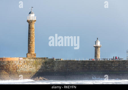 Whitby, Yorkshire, UK. 11. Februar, 2019. Großbritannien Wetter. Whitby, North Yorkshire, England. 11. Februar 2019. Die Besucher der North Yorkshire coast in Whitby genießen einen hellen, aber kalt Spaziergang entlang der Küste mit den alten Leuchtturm und Hafen im Hintergrund. Alan Beastall // Alamy leben Nachrichten Stockfoto