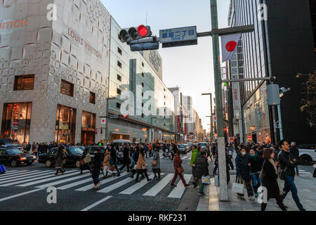Tokyo Ginza im golden hour. Blick entlang der Straße Kreuzung Ginza 2, Menschen mit Zebrastreifen, mit Louis Vuitton und Matsuya Ginza Store, Andere. Stockfoto