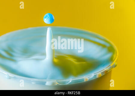 High speed Foto eines Milch Tropfen auf gelben Hintergrund im Studio Stockfoto