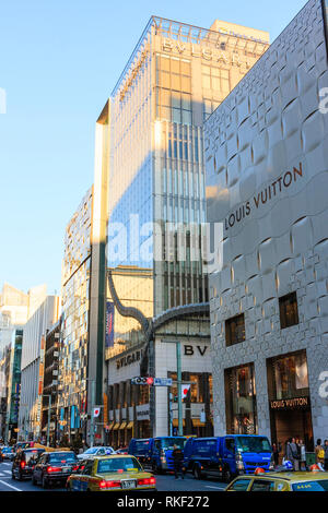 Tokyo, Ginza im golden hour. Blick entlang der Straße, Louis Vuitton und die bvlgari Flagship Store Gebäude mit Taxis an der roten Ampel vor. Stockfoto