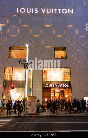 Tokyo, Ginza. Die Louis Vuitton store Gebäude auf der anderen Seite der Straße, nachts beleuchtet, mit Pflaster besetzt mit Menschen. Zebrastreifen. Stockfoto