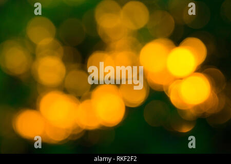 Gelbe Bokeh Kugeln abstrakte Textur auf grünem Hintergrund. Farbenfroh. De fokussierte Hintergrund. Helles Licht verschwimmen. Runde Punkte. Stockfoto
