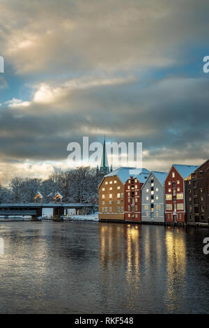 Alte hölzerne Gebäude, Zeitschriften, am Ufer des Flusses Nidelva, Winter in Trondheim, Norwegen. Stockfoto