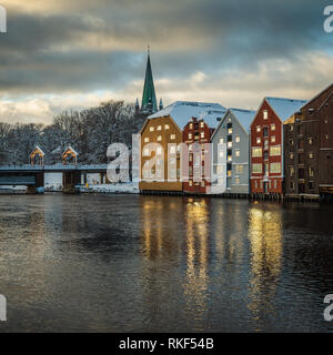 Alte hölzerne Gebäude, Zeitschriften, am Ufer des Flusses Nidelva, Winter in Trondheim, Norwegen. Stockfoto