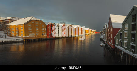 Alte hölzerne Gebäude, Zeitschriften, am Ufer des Flusses Nidelva, Winter in Trondheim, Norwegen. Stockfoto