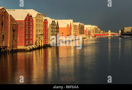 Alte hölzerne Gebäude, Zeitschriften, am Ufer des Flusses Nidelva, Winter in Trondheim, Norwegen. Stockfoto