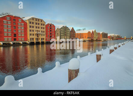 Alte hölzerne Gebäude, Zeitschriften, am Ufer des Flusses Nidelva, Winter in Trondheim, Norwegen. Stockfoto