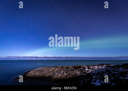 Norden leuchtet Aurora Borealis von Atlantic Ocean Road - Atlanterhavsveien im Winter Nacht gesehen. Norwegische Winter. Schönen Sternenhimmel und Lämpchen leuchten grün. Stockfoto