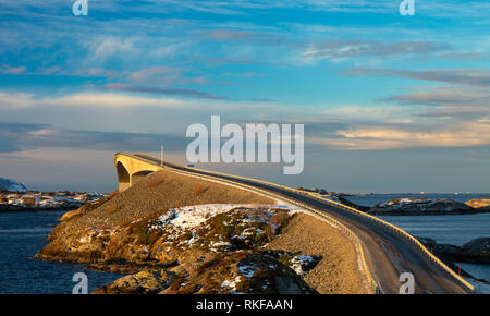 Atlantic Ocean Road - Atlanterhavsvegen im Winter sonniger Tag. Berühmte hohe Brücke über das Meer genannt Storseisundbrua und schöne verschneite Berge in einer Stockfoto