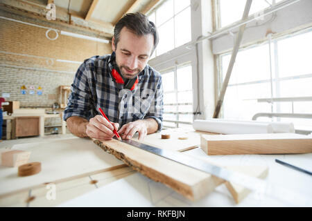 Zeichnen von Geraden mit Lineal, die während der Arbeit mit Holzbrett Stockfoto