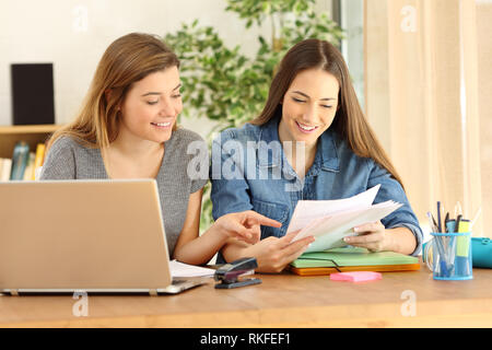 Zwei glückliche Studierende Prüfen und Vergleichen von Notizen auf dem Schreibtisch zu Hause Stockfoto