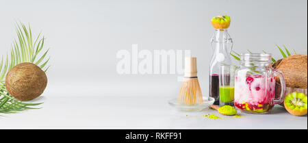 Iced vegan Fusion Matcha grüner Tee Latte mit Kokosmilch. Matcha espresso Fusion Drink mit rosa Früchte Saft bei grauen Hintergrund. Gesunde beneficia Stockfoto
