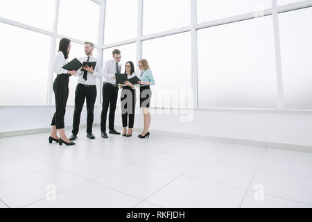 Diskutieren Mitarbeiter geschäftliche Dokumente in der Lobby stehend Stockfoto