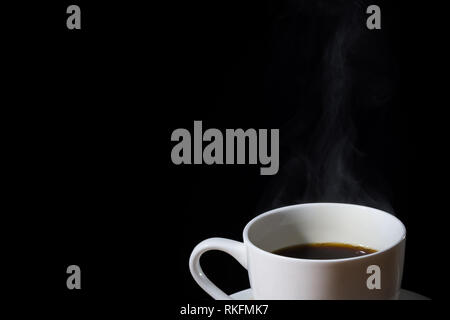 Weiße Tasse Kaffee mit Dampf oder Dunst und in Schwarz isoliert. Stockfoto