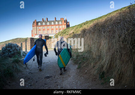 Reifen Surfer ihre Surfbretter zu Fuß bis zum Strand Hotel fistral in Newquay Cornwall. Stockfoto