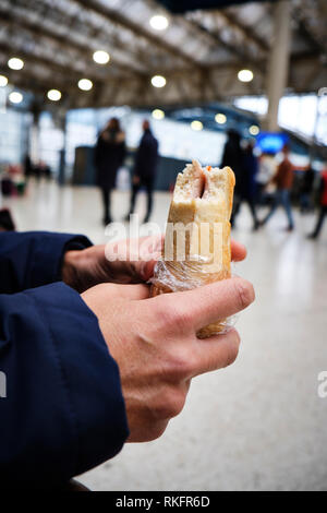 Nahaufnahme von einem kaukasischen Mann essen ein Sandwich in einem Bahnhof oder einer Straßenbahn-Station Stockfoto