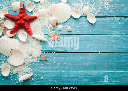 Sommer Hintergrund rot Seesterne und Muscheln auf Blau Holz- Hintergrund Stockfoto